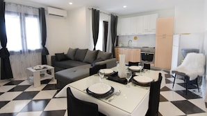 A modern living room with a sofa, dining table set for two, and a kitchen in the background. - Stylish Renovated Vacation Flat With Terrace (Umag)