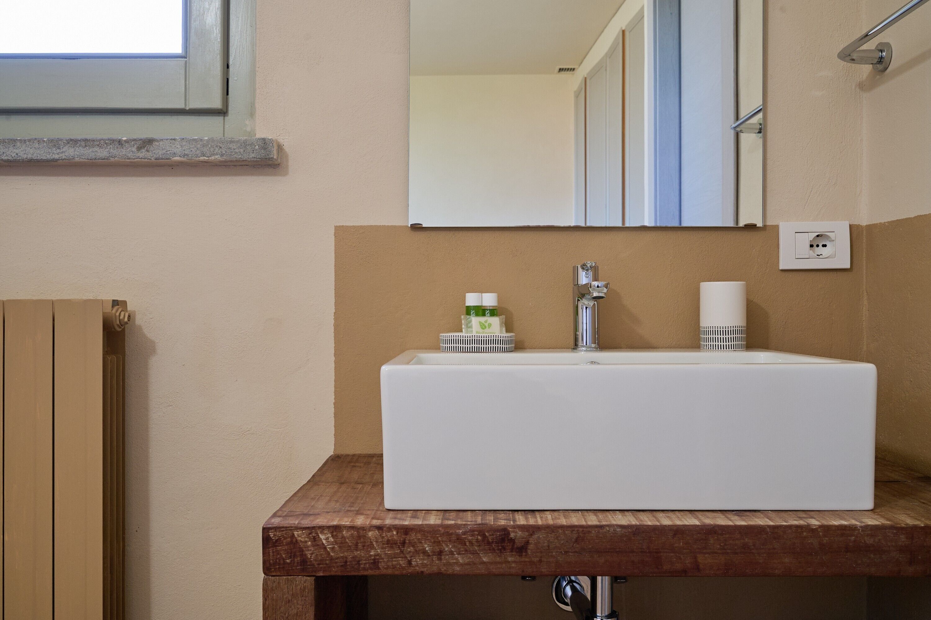 Un baño con un lavamanos blanco, encimera de madera y un espejo encima.