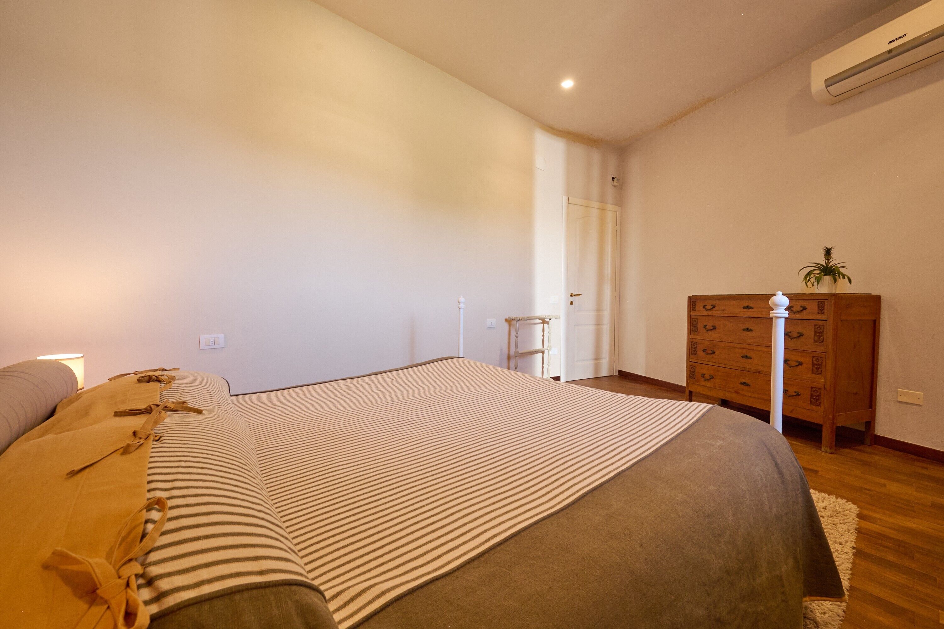 A bedroom with a bed, dresser, and a door leading to another room.