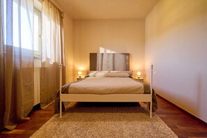 Ein Schlafzimmer mit einem Bett, Nachttischlampen, einem Fenster mit Vorhängen und einem Teppichboden.
