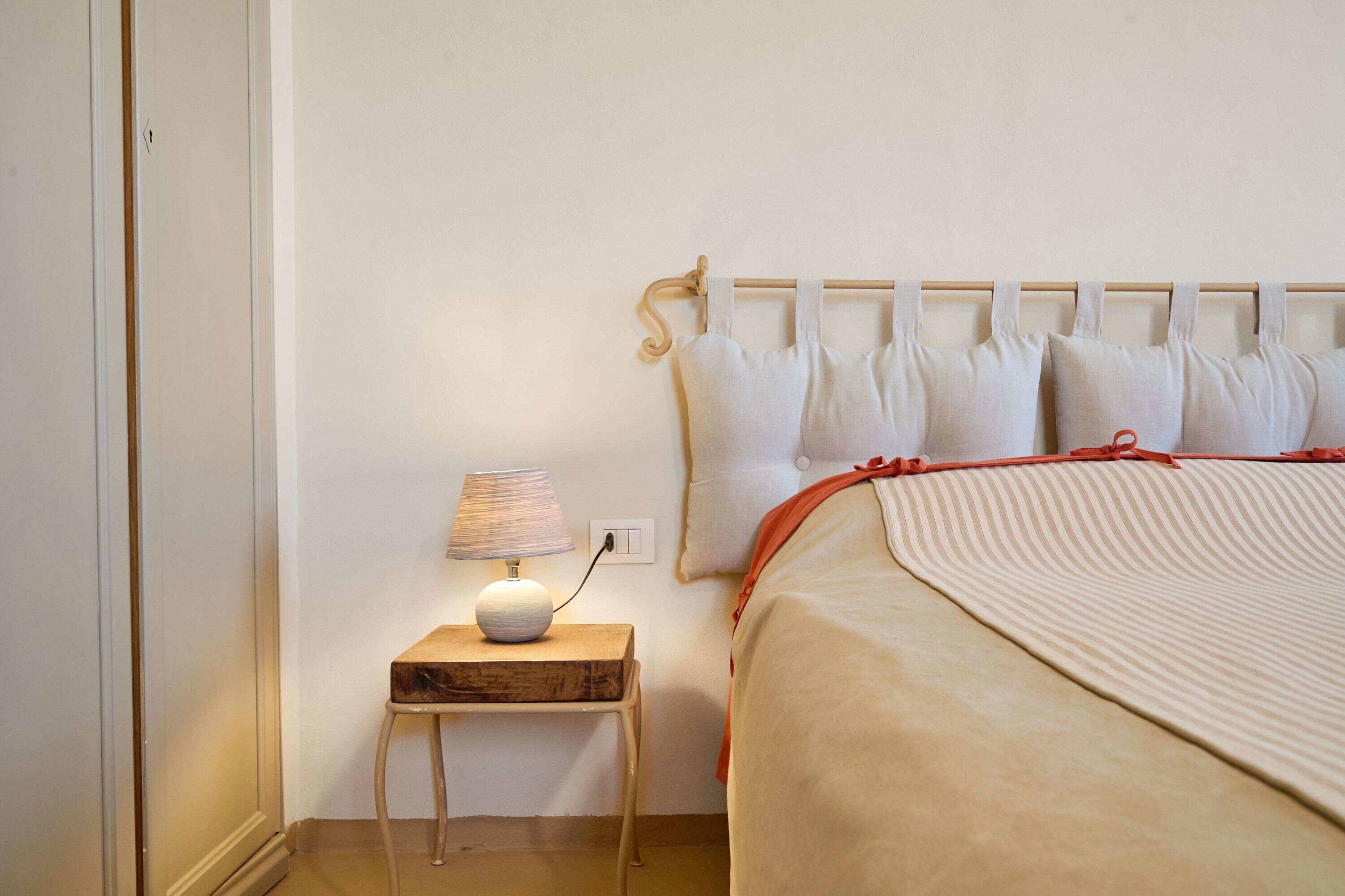A bedroom with a bed, pillows, a bedside table with a lamp, and a wooden headboard.
