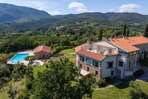 A two-story house with a swimming pool, surrounded by lush greenery and mountains. - Apartment 'Agriturismo Il Ghiaccio - Oleandro' with Sea View, Wi-Fi and Air Conditioning (Suvereto)