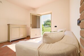 A room with a bed, a cabinet, and a sliding glass door leading to an outdoor area. - Apartment 'Agriturismo Il Ghiaccio - Quercia' with Shared Pool, Wi-Fi and Air Conditioning (Suvereto)