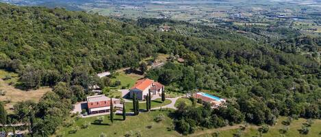Una extensa propiedad con varias construcciones, amplios campos verdes y un telón de fondo montañoso.