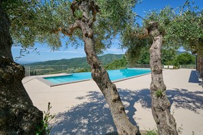 A swimming pool with a view of hills, surrounded by trees and a fence. - Apartment 'Agriturismo Il Ghiaccio - Quercia' with Shared Pool, Wi-Fi and Air Conditioning (Suvereto)