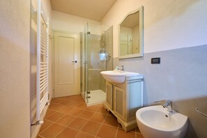 Et badeværelse med glasbrusekabine, vask og brusertoilet.