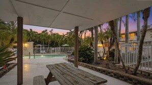 A covered outdoor area with a pool, wooden picnic table, and palm trees. - Under 1 Mile to Siesta Key Beach | Beach Gear Included | Pool | Sleeps 4 (Sarasota)