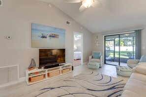 Ein Wohnzimmer mit Fernseher, Sofa und Blick ins Freie.
