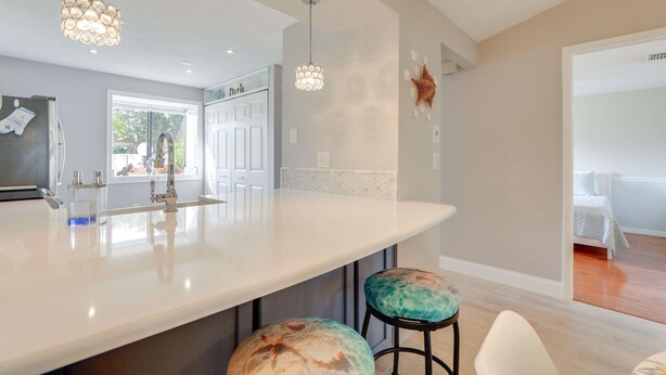 Una cocina moderna con una isla grande, luces colgantes y vista al comedor.