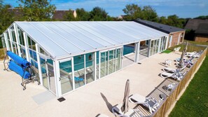A modern outdoor pool area with a glass enclosure, lounge chairs, and a blue water slide. - Vvf Villages Veules Les Roses (Veules-les-Roses)
