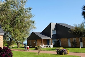 A building with a brick facade, a sloped roof, and a patio area with outdoor seating.