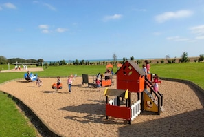 A playground with sand play area, climbing structures, and a slide.