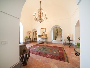 Ein geräumiges Foyer mit einer Kandelaber, einem gemusterten Teppich und einer Treppe mit aufwendiger Geländer.