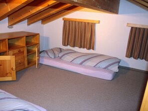 A small, single-room accommodation with a loft bed, a wooden dresser, and a futon bed. - Plaun Pazzola mit Garage Bösch, (Sedrun/Rueras), 684.01 by Interhome (Rueras Dieni)