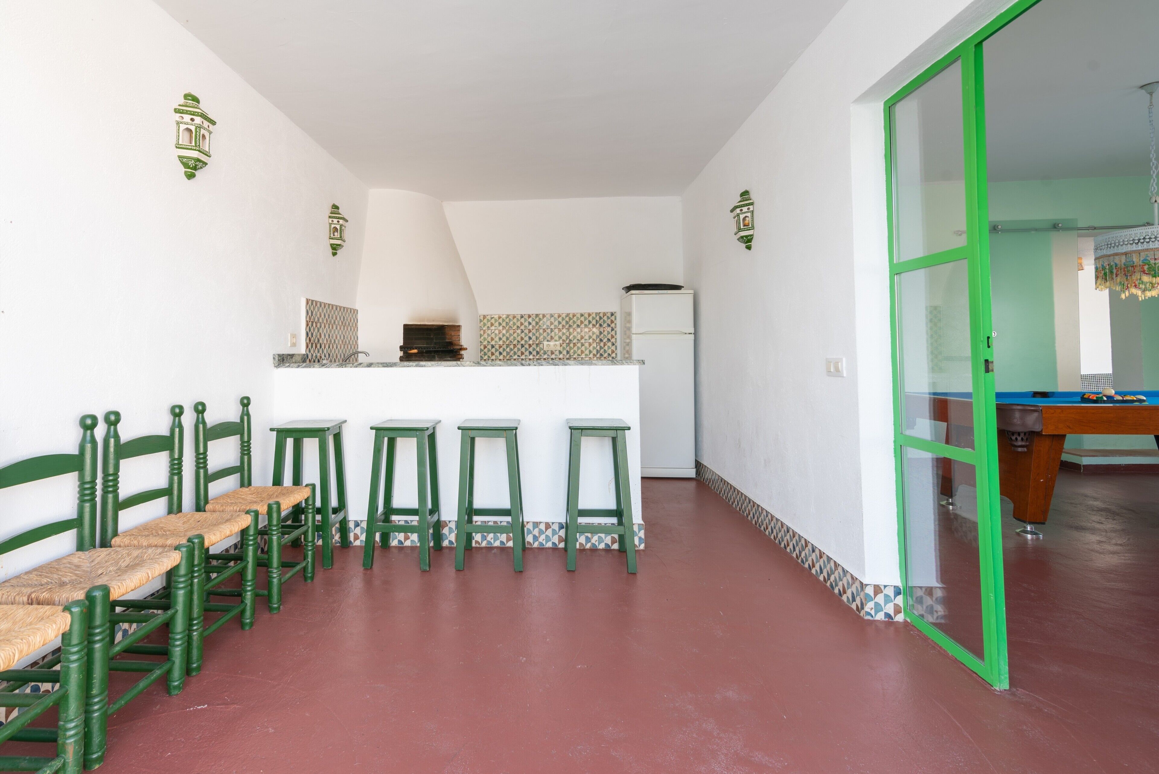 Una habitación con espacio de cocina, una mesa de comedor con sillas y una mesa de billar.