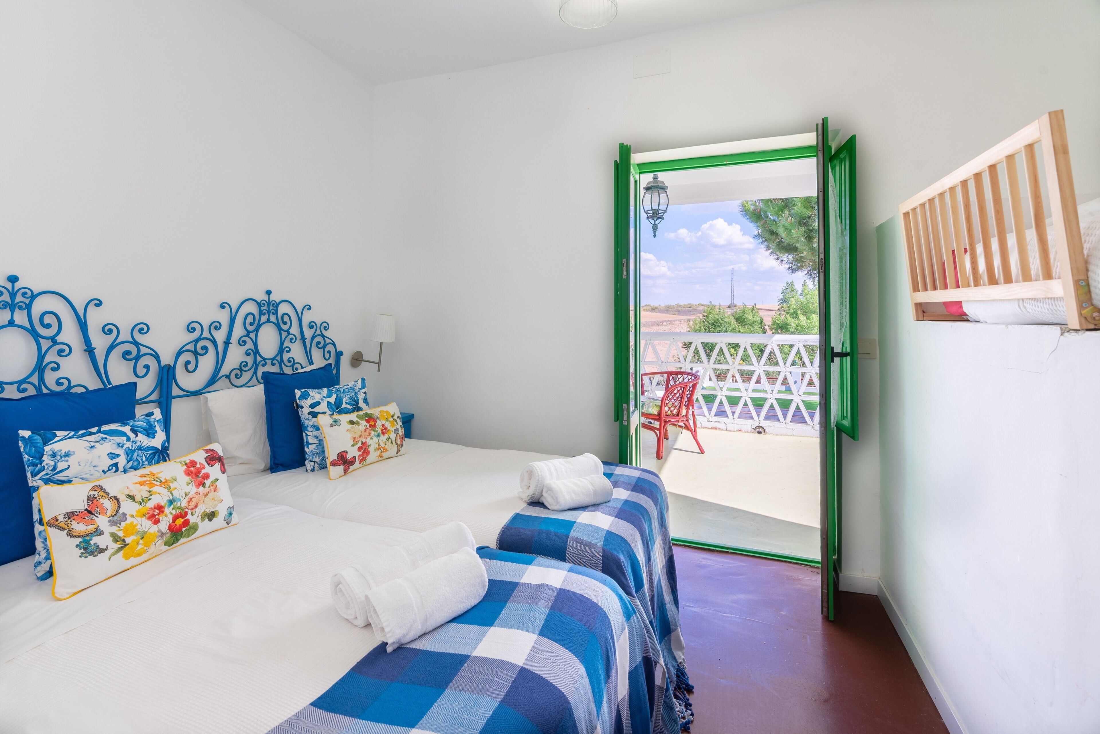 Un dormitorio con dos camas, una puerta con marco verde y vistas al exterior.
