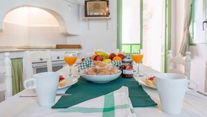 Una mesa de desayuno con un bol de muffins, un plato de fruta y un vaso de zumo de naranja.