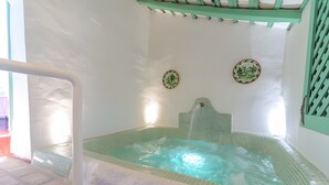 Un jacuzzi con interior de azulejos, una cubierta de madera y techo verde.