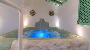 Un jacuzzi con borde de azulejos, estructura de techo de madera y dos placas decorativas en las paredes.