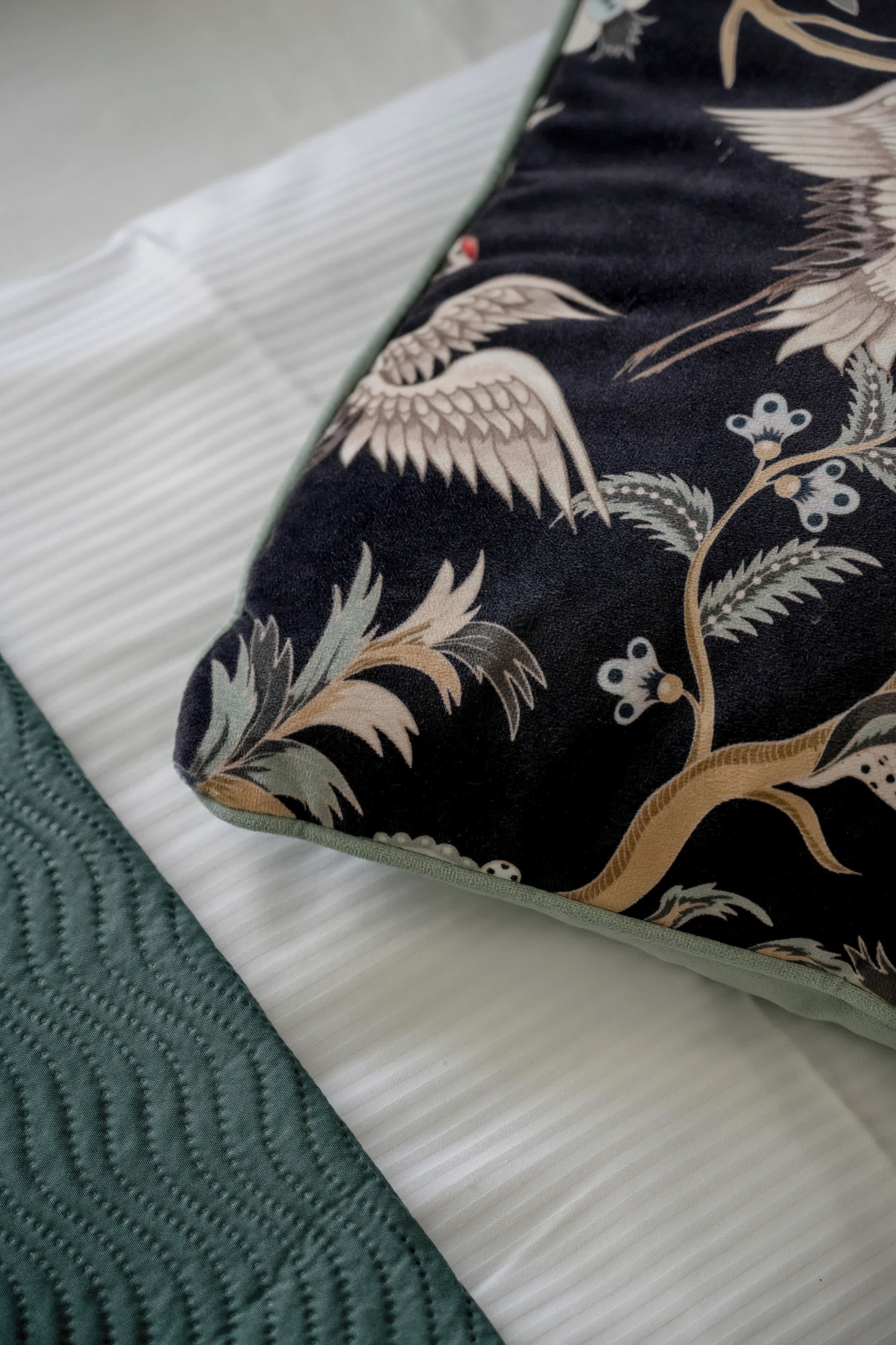 A pillow with a floral pattern and a textured green blanket.
