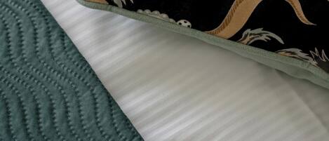 A pillow with a floral pattern and a textured green blanket.