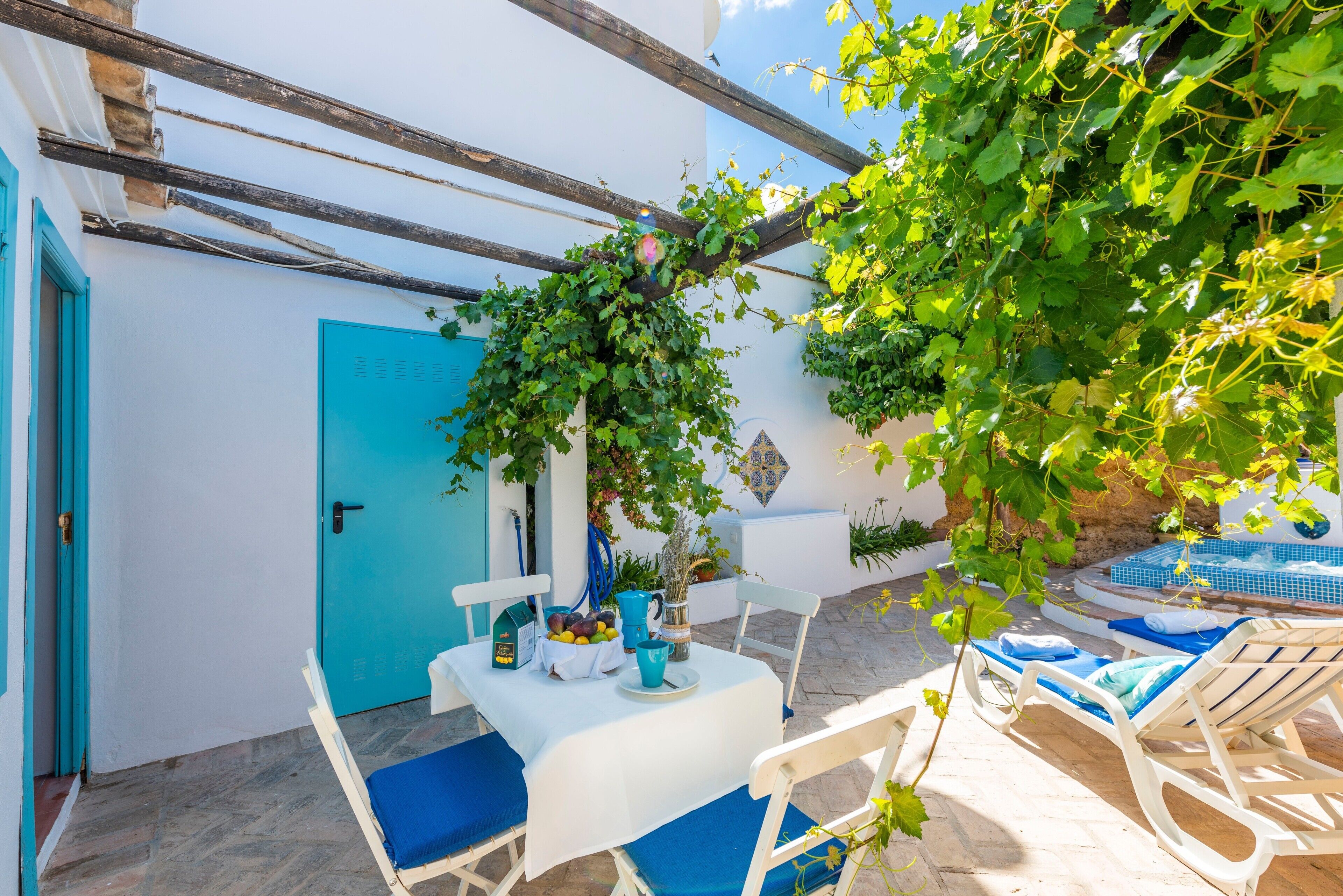 A patio with a table set for dining, a chair, a lounge chair, and a door.