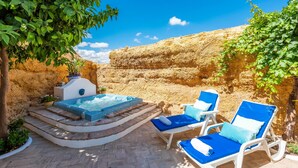 Un jacuzzi, sillas de descanso y una pared de piedra.