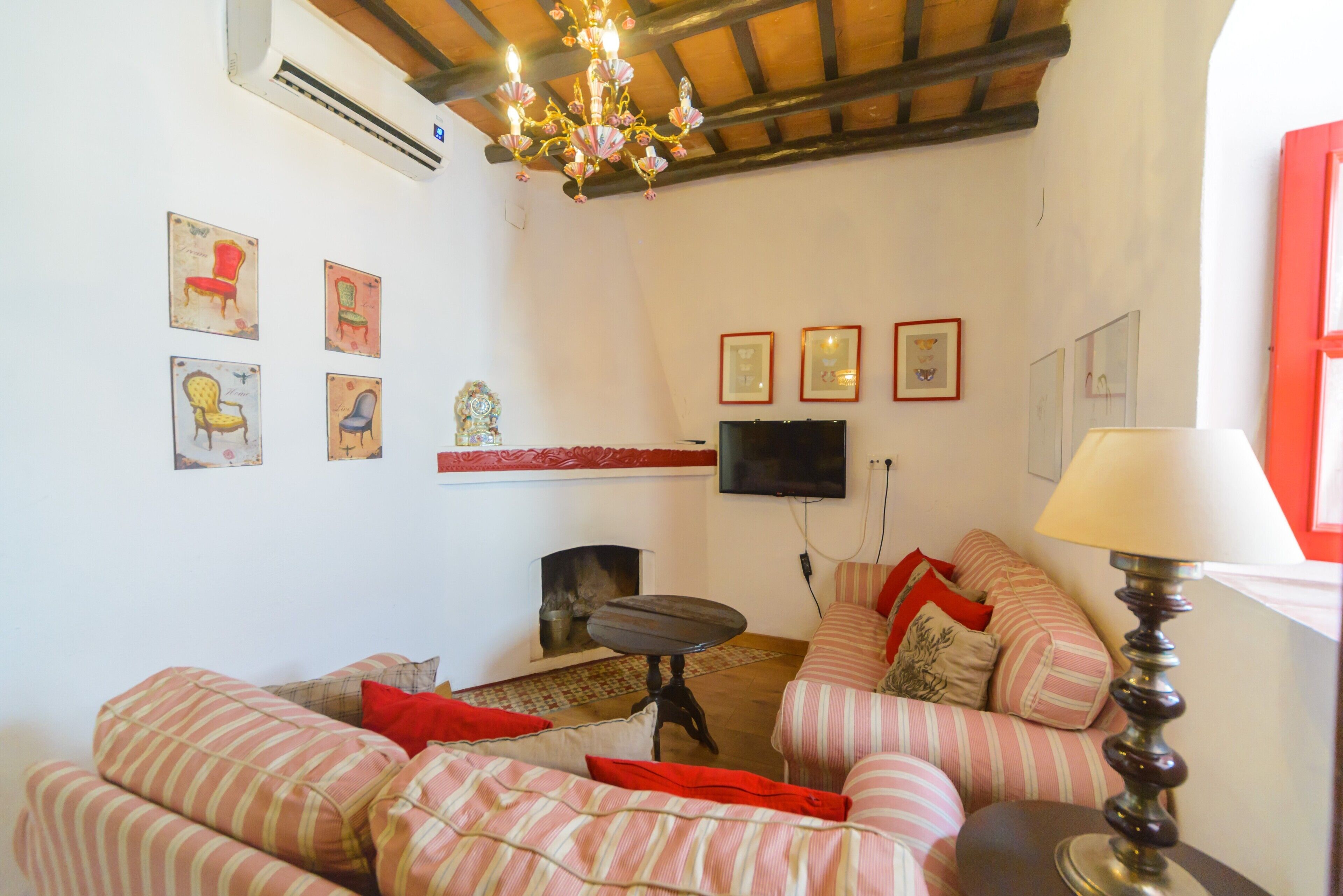 A living room with striped sofas, a fireplace, a flat-screen TV, and wall-mounted artwork.