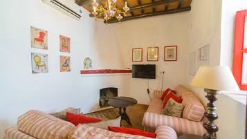 A living room with striped sofas, a fireplace, a flat-screen TV, and wall-mounted artwork.