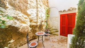 A narrow courtyard with a red door, a small table with a chair, and a potted plant. - Casa De La Fredeswinda: Charming Andalusian Rural Getaway (Peñaflor)