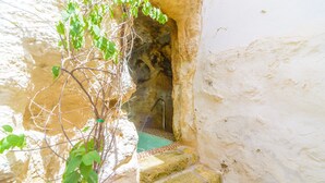 A narrow stone staircase leading to a cave-like interior with a tiled floor and a metal ladder. - Casa De La Fredeswinda: Charming Andalusian Rural Getaway (Peñaflor)