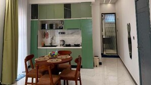 Ein modernes Wohnzimmer mit Essbereich, Küchenschränken in Grün und einer Tür zu einem anderen Raum.
