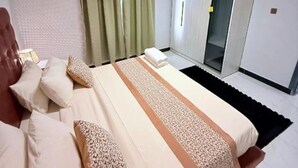 Ein Schlafzimmer mit einem Bett, Kissen, einem Nachttisch, einem Fenster mit Vorhängen und einem Kleiderschrank.