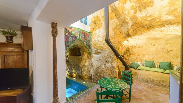 A stone-walled interior with a pool, green furniture, and a wooden cabinet. - Casa de la Robledo, Intimate Rural Getaway in Peñaflor (Peñaflor)