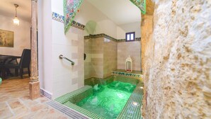 A bathroom with a green-tiled jacuzzi, a shower area, and a decorative archway. - Casa de la Robledo, Intimate Rural Getaway in Peñaflor (Peñaflor)
