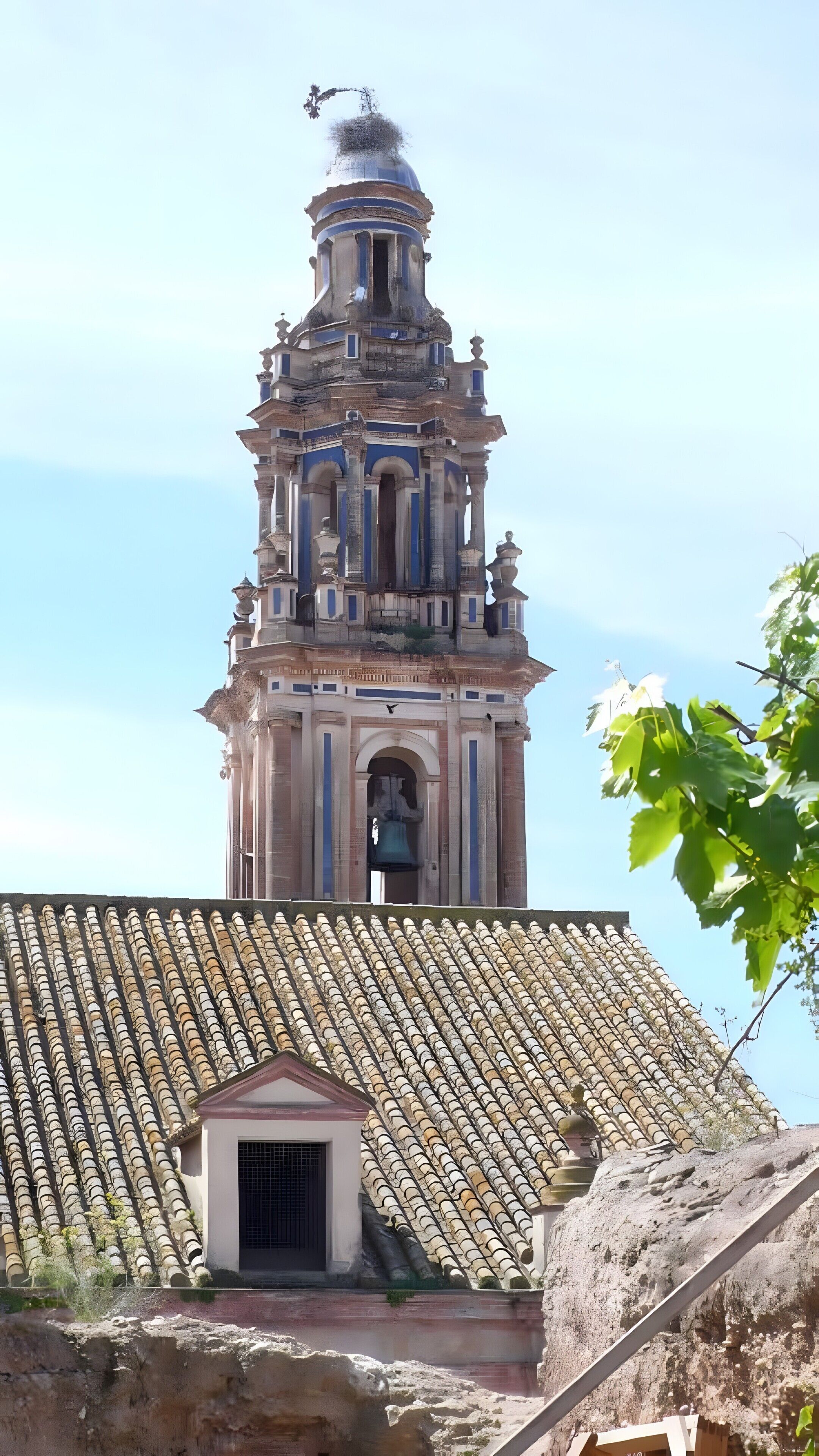 A historic bell tower with intricate architecture, a small bell, and a tiled roof.