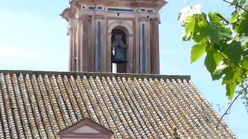 A historic bell tower with intricate architecture, a small bell, and a tiled roof.