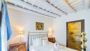 A hotel room with a bed, two bedside tables, a painting on the wall, and a mirror with a stone wall. - Casa de la Robledo, Intimate Rural Getaway in Peñaflor (Peñaflor)
