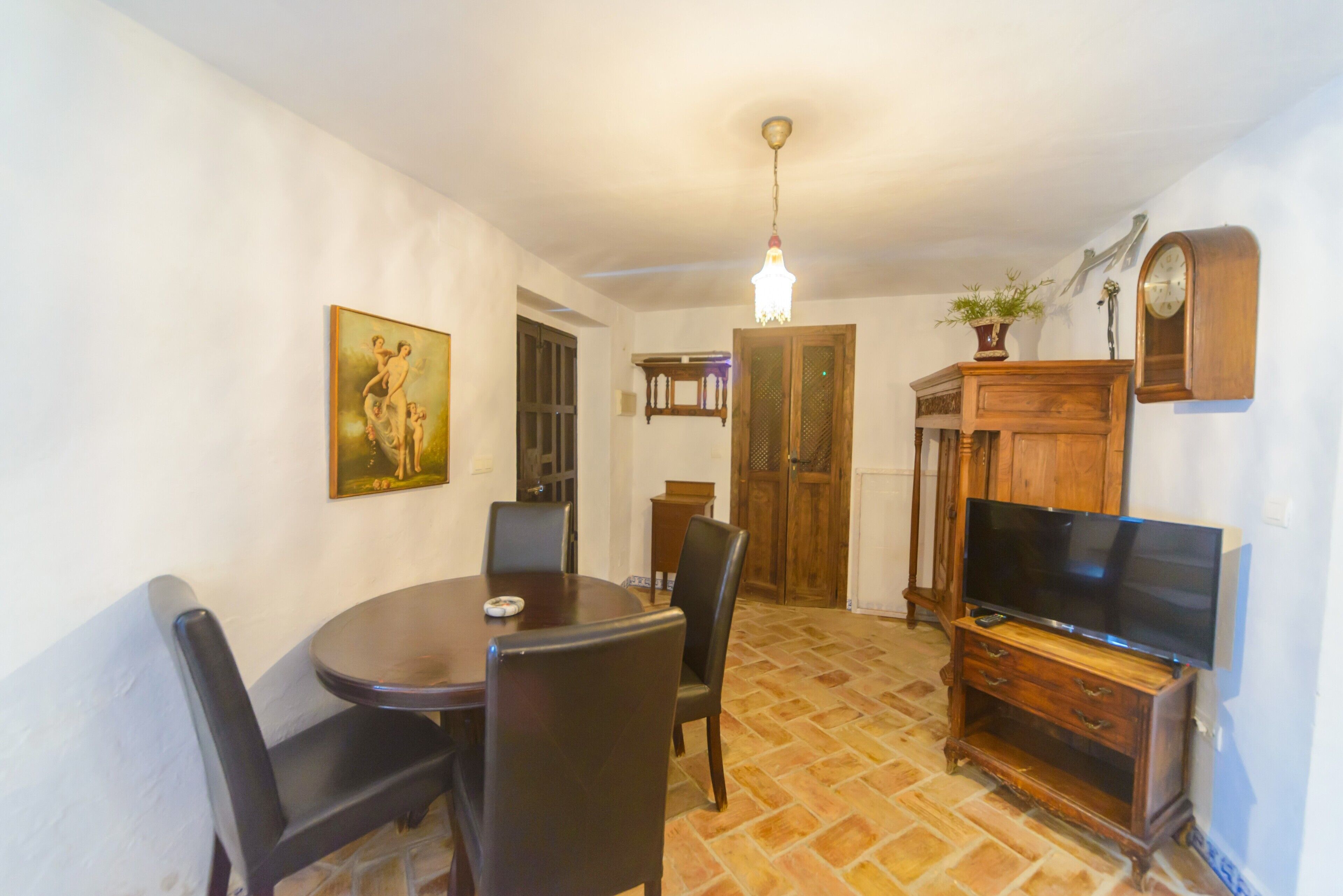 Un comedor con una mesa redonda, sillas, un televisor y un armario de madera.