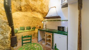 A rustic kitchen with a stone wall, a wooden table, and a green chair. - Casa de la Robledo, Intimate Rural Getaway in Peñaflor (Peñaflor)