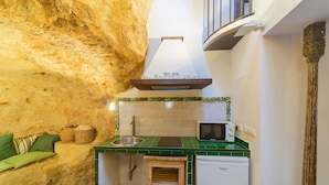 A compact kitchen with a stone wall, green tiled backsplash, a microwave, and a small refrigerator. - Casa de la Robledo, Intimate Rural Getaway in Peñaflor (Peñaflor)