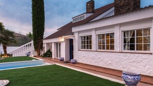 A house with a stone facade, a swimming pool, and a well-maintained lawn.