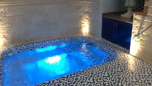 A hot tub with a blue light, a tiled floor, and a blue cabinet.
