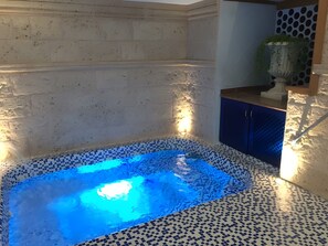 Ein Whirlpool mit blauem Licht, gefliestem Boden und einem blauen Schrankschrank.