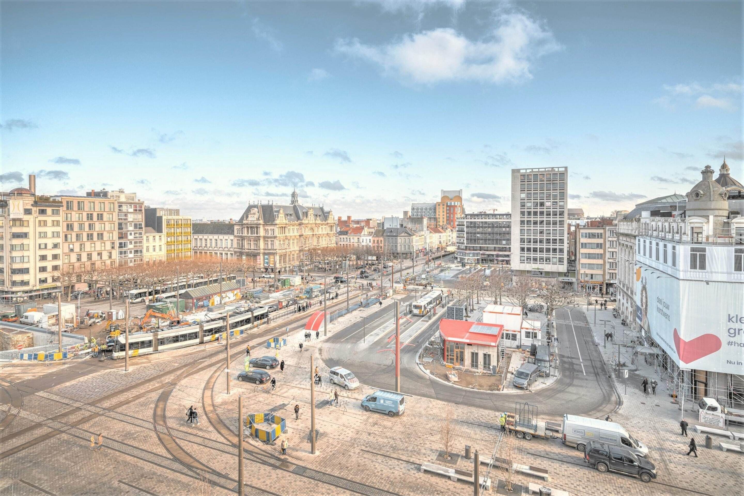 Un paisatge urbà amb una línia de tram, edificis i un cartell publicitari gran.