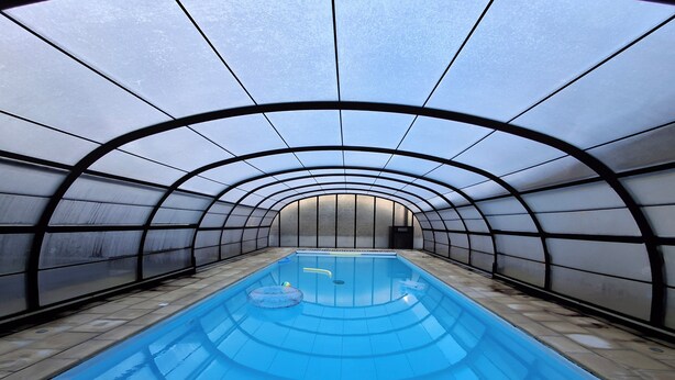 A swimming pool with a glass ceiling, surrounded by walls with a grid pattern. - Villa des Halles - 14 to 15 pers - Private swimming pool (Plouescat)