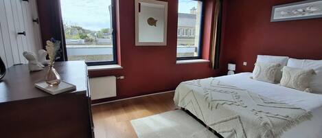 A bedroom with a bed, a desk, a window, and a radiator.