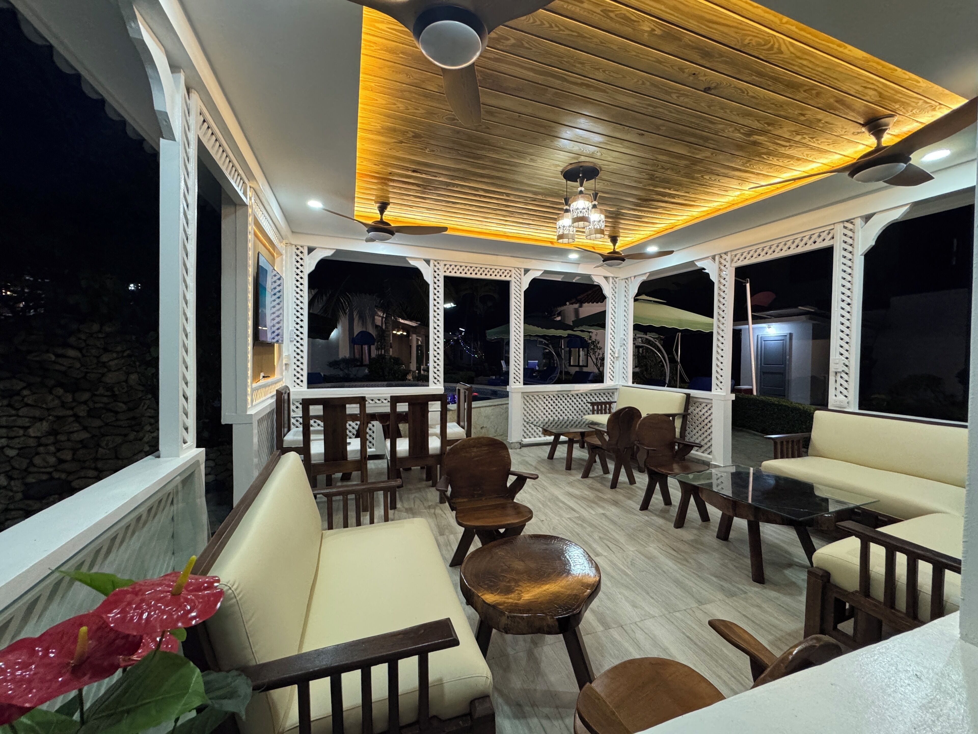 An outdoor seating area with tables and chairs, a ceiling fan, and a view of the night sky.
