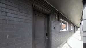 A corridor with a closed door, a window, and a brick wall. - New Columbus Studio Steps from Downtown (Columbus)