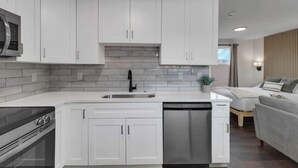 A modern kitchen with white cabinets, a stainless steel sink, and a dishwasher. - New Columbus Studio Steps from Downtown (Columbus)